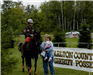 Woman holds child while petting horse
