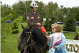 Female officer on a brown horse with a child petting horse