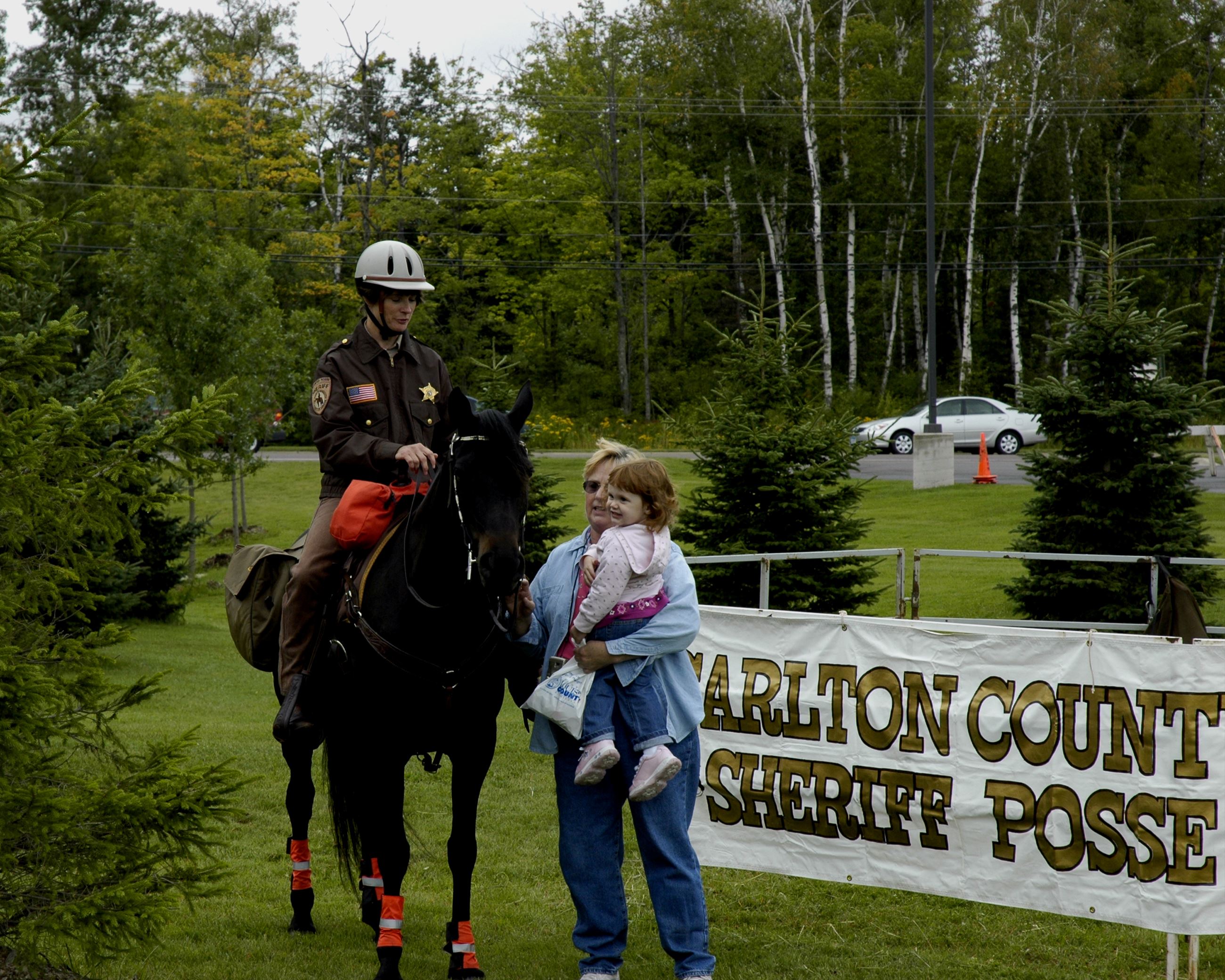 Woman holds child while petting horse